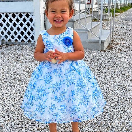 Azyrah is registered to the contest to win money with this photo: child, girl, toddler, smiling, portrait, outdoor, dress, floral_dress, blue_bow, standing, gravel, porch, house, summer, fashion, happy, shoes, garden, daylight, person