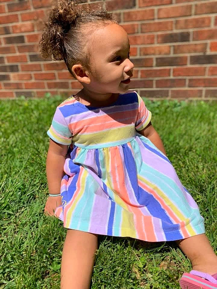 Alaiyah is registered to the contest to win money with this photo: baby_toddler_clothing, brick, brickwork, child, day_dress, dress, electric_blue, face, grass, happy, leaf, one_piece_garment, outerwear, people_in_nature, person, pink, plant, shoulder, sleeve, summer