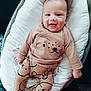 baby, infant, smile, cute, clothing, bear_print, onesie, cushion, baby_seat, comfortable, happy, child, portrait, indoors, fabric, pattern, sleepwear, newborn, person, apparel