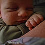 baby, sleeping, close_up, face, hand, fist, skin, arm, clothing, peaceful, resting, soft_lighting, infant, portrait, tender_moment, cute, young_child, indoors, human, child