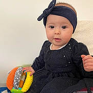 Luiza participe au concours pour gagner de l'argent avec cette photo : baby, infant, child, headband, rattle, dress, portrait, cute, big_eyes, face, hand, sitting, blank_wall, blanket, fabric, indoor, soft_toy, curious_expression, cheeks, skin