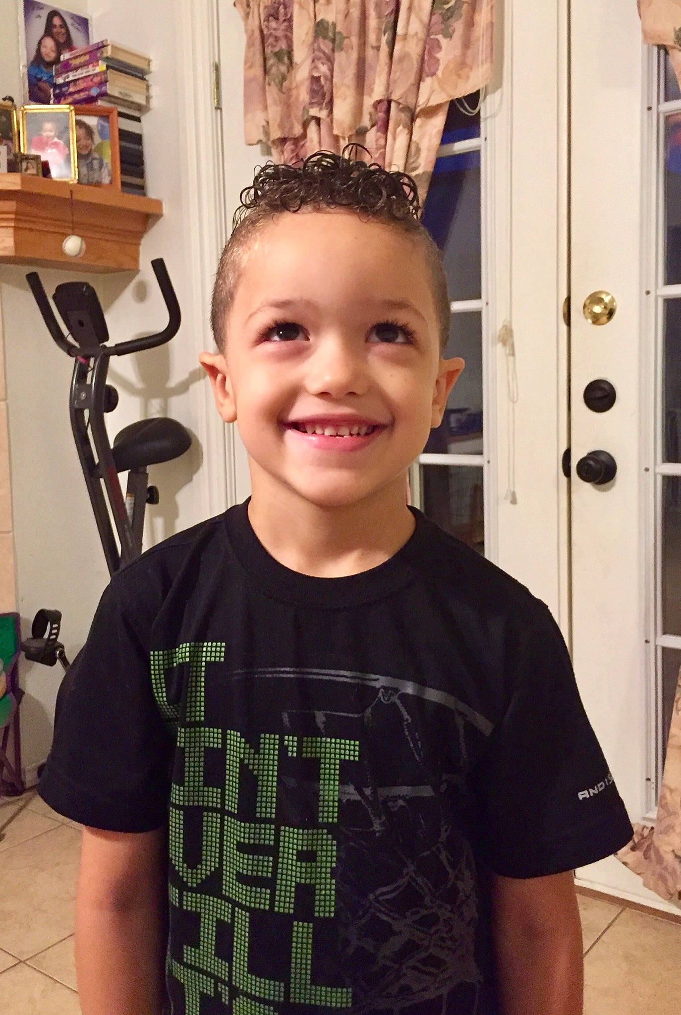 Emilio is registered to the contest to win money with this photo: arm, child, chin, cool, design, ear, forehead, hair, hairstyle, head, joy, neck, pattern, person, room, shoulder, smile, standing, t_shirt, toddler