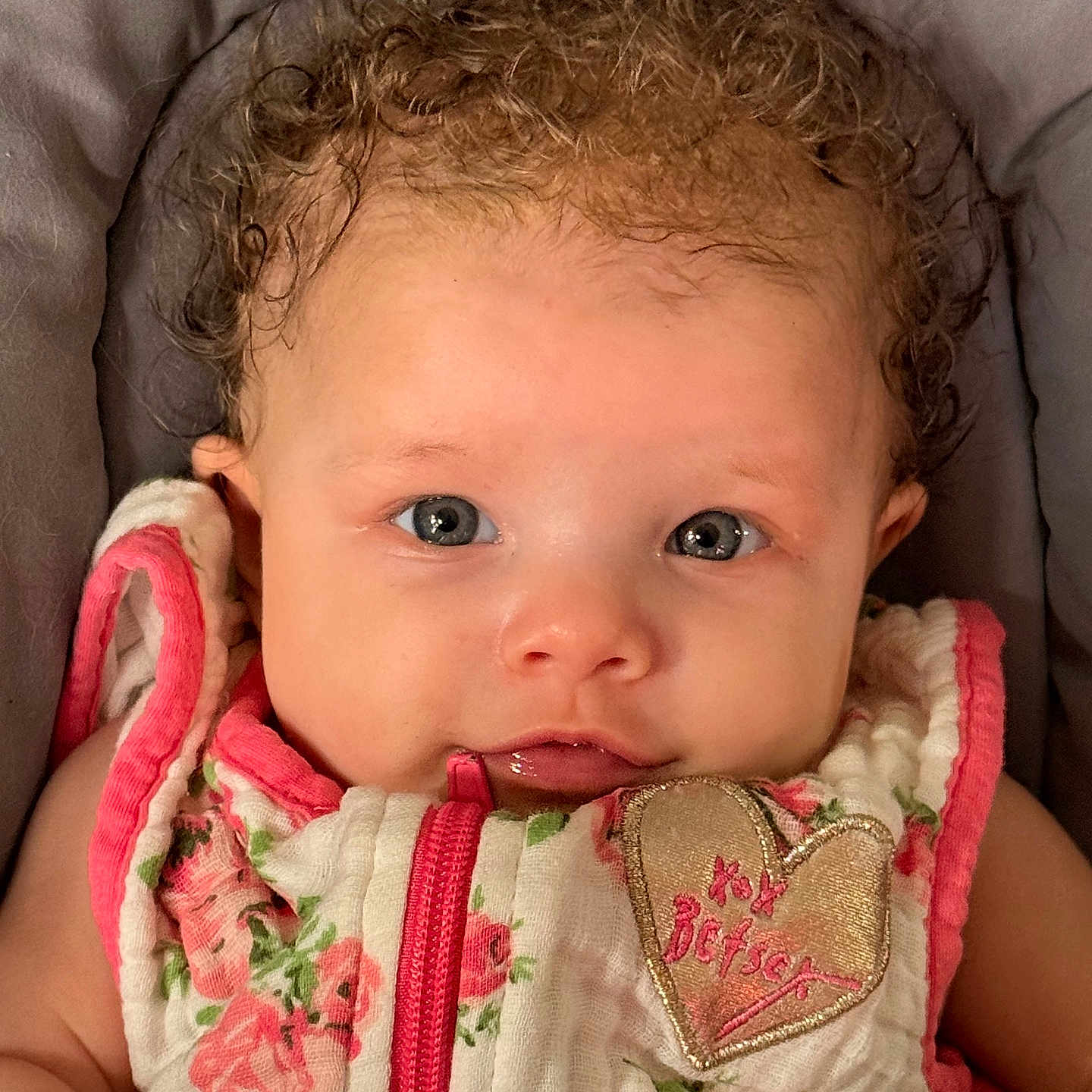 Guinevere joined the competition — help win amazing prizes! adorable, apparel, baby, blue_eyes, child, close_up, clothing, curly_hair, cute, fabric, floral_outfit, heart_patch, infant, lying_down, person, pink, portrait, soft_cushion, white, young