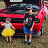 Kaela Robinson joined the competition — help win amazing prizes! child, toddler, boy, girl, yellow_tutu, red_car, open_hood, grass, outdoor, sunny, sign, hat, sunglasses, tshirt, shorts, shoes, smile, tree, building, event