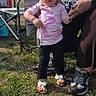 toddler, child, woman, hand_holding, outdoor, grass, chair, pink_shirt, unicorn_design, black_leggings, sandals, adult, footwear, sunlight, daytime, person, nature, family, support, casual_clothing