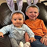 Maverick is registered to the contest to win money with this photo: children, baby, toddler, siblings, smiling, portrait, bunny_ears, headband, bunny_costume, orange_shirt, baby_clothing, leather_couch, sitting, indoors, home_interior, family, happy, cute, sock, photograph