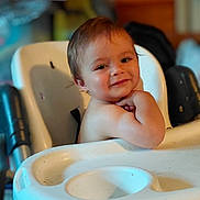 Maverick is registered to the contest to win money with this photo: baby, infant, child, high_chair, smiling, portrait, indoor, seated, brown_hair, face, person, baby_tray, furniture, home, photograph, phone_screenshot, gallery_interface, black_border, happy, cute