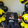 baby, batman_costume, child, balloons, yellow, black, party, gift_bags, mask, cape, costume, indoor, carpet, chair, celebration, superhero, toddler, cute, fun, portrait