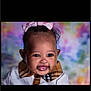 adorable, baby, black_hair, bow, child, closeup, clothing, colorful_background, cute, earrings, face, happy, infant, pink_bow, plaid_collar, portrait, smile, studio_lighting, toddler, young_child