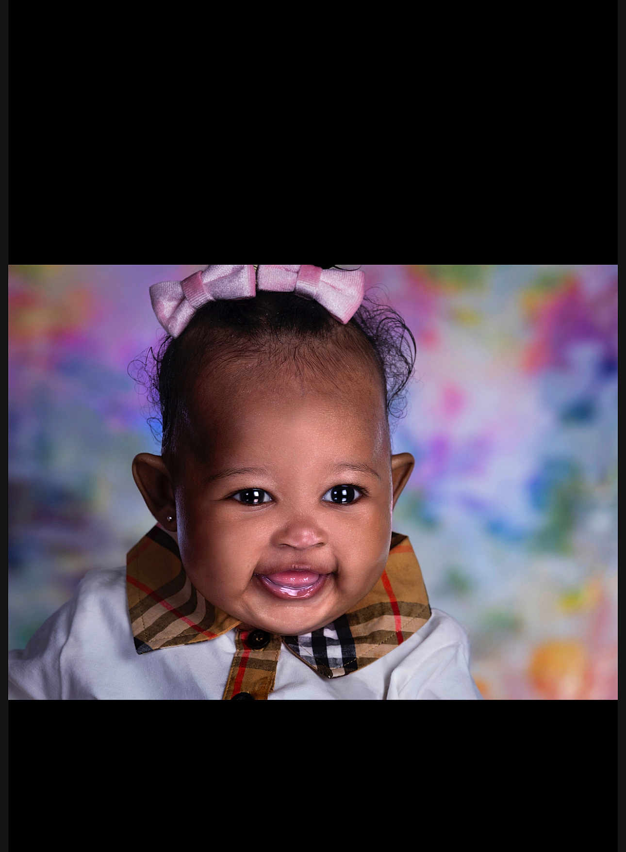 Deyana is registered to the contest to win money with this photo: adorable, baby, black_hair, bow, child, closeup, clothing, colorful_background, cute, earrings, face, happy, infant, pink_bow, plaid_collar, portrait, smile, studio_lighting, toddler, young_child