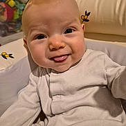 Alexis is registered to the contest to win money with this photo: baby, infant, face, tongue, smile, cushion, seat, clothing, onesie, child, indoor, cute, playful, expression, person, skin, head, eyes, happy, cozy