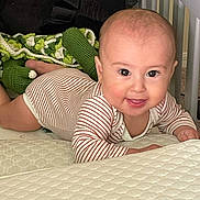 Alastar is registered to the contest to win money with this photo: baby, infant, smiling, tummy, mattress, striped_clothing, knitted_blanket, soft_toys, indoor, child, cute, happy, person, face, head, skin, eyes, mouth, hand, floor