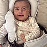 baby, infant, smile, onesie, heart_pattern, baby_seat, harness, cushion, comfort, child, cute, portrait, happy, indoor, clothing, person, face, seatbelt, straps, young