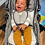 Landon is registered to the contest to win money with this photo: baby, bear_slippers, brown_pants, child, cozy, curly_hair, cute, fabric, happy, indoor, infant, laughing, person, play_mat, seatbelt, smiling, striped_shirt, stroller, toy, wooden_floor