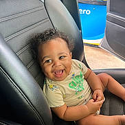 Landon is registered to the contest to win money with this photo: baby, child, smiling, car_seat, curly_hair, dimple, tshirt, indoor, car_interior, happy, cute, infant, seatbelt, black_leather, automobile, seat, gas_station, door, joyful, portrait