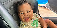 Landon is registered to the contest to win money with this photo: automobile, baby, black_leather, car_interior, car_seat, child, curly_hair, cute, dimple, door, gas_station, happy, indoor, infant, joyful, portrait, seat, seatbelt, smiling, tshirt