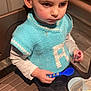 black_pants, blue_knit_vest, boy, brown_hair, casual_clothing, chair, child, eating, focused, food, indoor, knitting, long_sleeve_shirt, plastic_bowl, serious_expression, spaghetti, spoon, table, wooden_floor, young_child