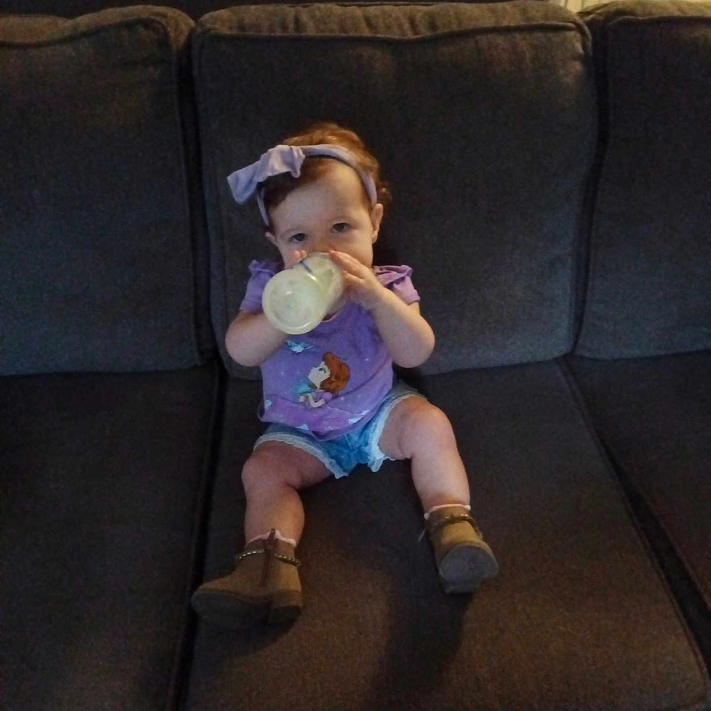 Isabella joined the competition — help win amazing prizes! child, toddler, baby, sitting, couch, bottle, drinking, milk, bow, purple_shirt, denim_shorts, boots, indoors, living_room, furniture, portrait, dark_lighting, brown_hair, infant, home