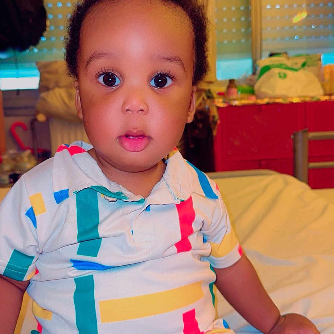 Raphaël participe au concours pour gagner de l'argent avec cette photo : baby, bed, blinds, casual, child, clothing, colorful, curious, face, furniture, indoor, person, portrait, room, sitting, sock, striped, toddler, window, young_child