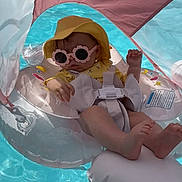 Sundae is registered to the contest to win money with this photo: baby, child, pool, inflatable, floaty, sunglasses, hat, yellow_clothing, water, sunshade, relaxing, summer, outdoor, sunny, cute, swimming_pool, floating, infant, toddler, vacation