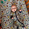 Bryce is registered to the contest to win money with this photo: baby, infant, crib, onesie, football, helmet, trophy, hand, foot, bedding, pattern, blue, yellow, orange, white, sleepwear, cute, child, smiling, lying_down