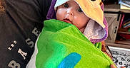 Bryce joined the competition — help win amazing prizes! baby, child, towel, hood, eyes, person, hand, indoor, door, clothing, fabric, colorful, portrait, holding, adult, furniture, table, photography, cute, expression