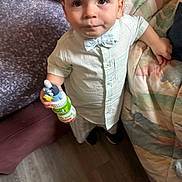 Malikye Gabrial joined the competition — help win amazing prizes! toddler, child, boy, indoor, shirt, bow_tie, juice_bottle, toy, floor, quilt, couch, carpet, curious, standing, furniture, face, clothing, hand, person, expression