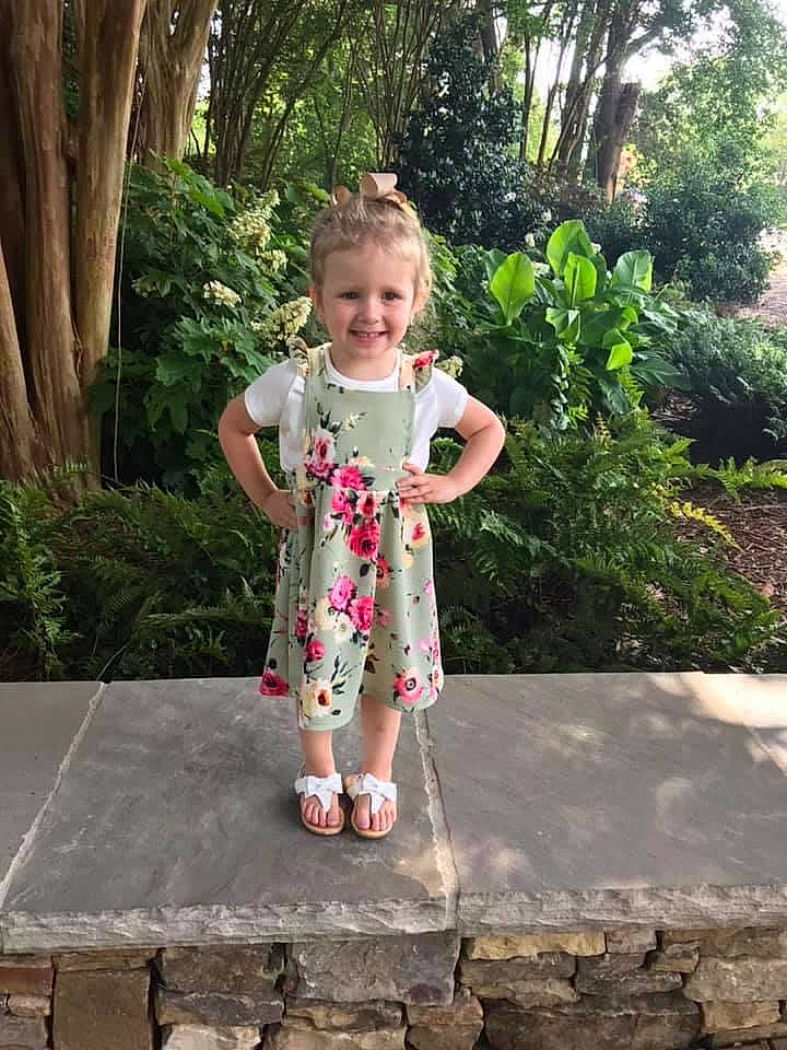 Lennox is registered to the contest to win money with this photo: baby_toddler_clothing, botany, dress, grass, happy, human_body, joint, joy, leaf, leg, leisure, mammal, people_in_nature, person, pink, plant, shoe, smile, standing, tree