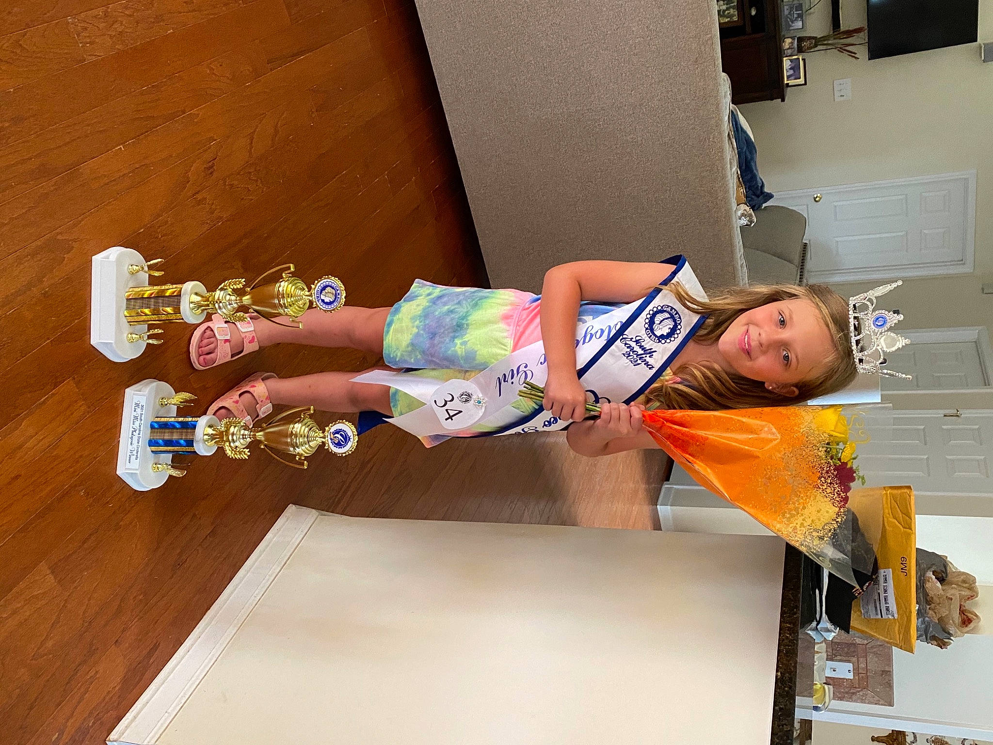 Kristan is registered to the contest to win money with this photo: child, dress, flooring, fun, happy, hardwood, human_leg, joy, knee, leisure, person, play, refrigerator, room, shelf, sportswear, t_shirt, textile, thigh, toddler