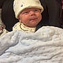 baby, infant, blanket, hat, car_seat, clothing, face, person, child, cozy, cute, indoors, soft_texture, newborn, smile, comfortable, resting, young, wrapped, seated