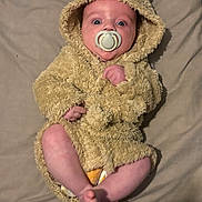 Charlie joined the competition — help win amazing prizes! baby, infant, pacifier, hooded_outfit, bear_costume, fuzzy_texture, blanket, bedding, portrait, lying_down, eyes_wide, cute, hands, feet, toes, skin, indoors, soft_toy_style, sleepwear, cozy
