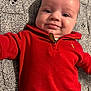Charlie is registered to the contest to win money with this photo: baby, infant, child, red_clothing, zip_sweater, knit_blanket, portrait, smile, cheeks, eyes, face, lying_down, cozy, indoor, fabric_texture, closeup, skin, collar, cute, casual_snap