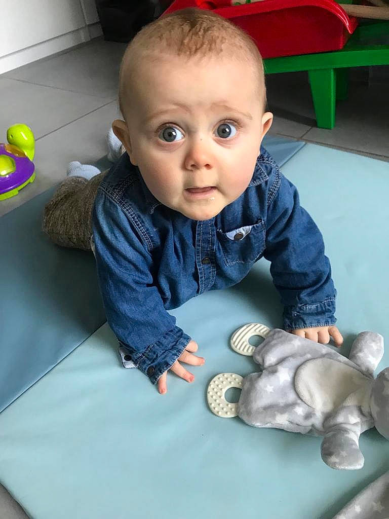 Sam participe au concours pour gagner de l'argent avec cette photo : arm, baby, baby_toddler_clothing, cheek, child, comfort, face, finger, floor, flooring, fun, hand, head, people, person, product, sitting, skin, surprise, toddler