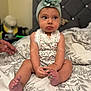 baby, bed, bedspread, child, cute, expression, fabric, feet, fingers, floral_outfit, flower_headband, hand, headwear, indoors, infant, person, portrait, room, sitting, skin