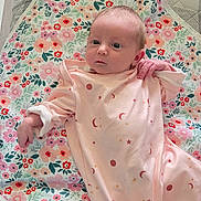 Rylynn is registered to the contest to win money with this photo: baby, infant, newborn, child, onesie, pink_clothing, floral_blanket, blanket, bedding, quilt, portrait, face, head, eyes_open, hand, lying_down, indoor, soft_lighting, cute, peaceful