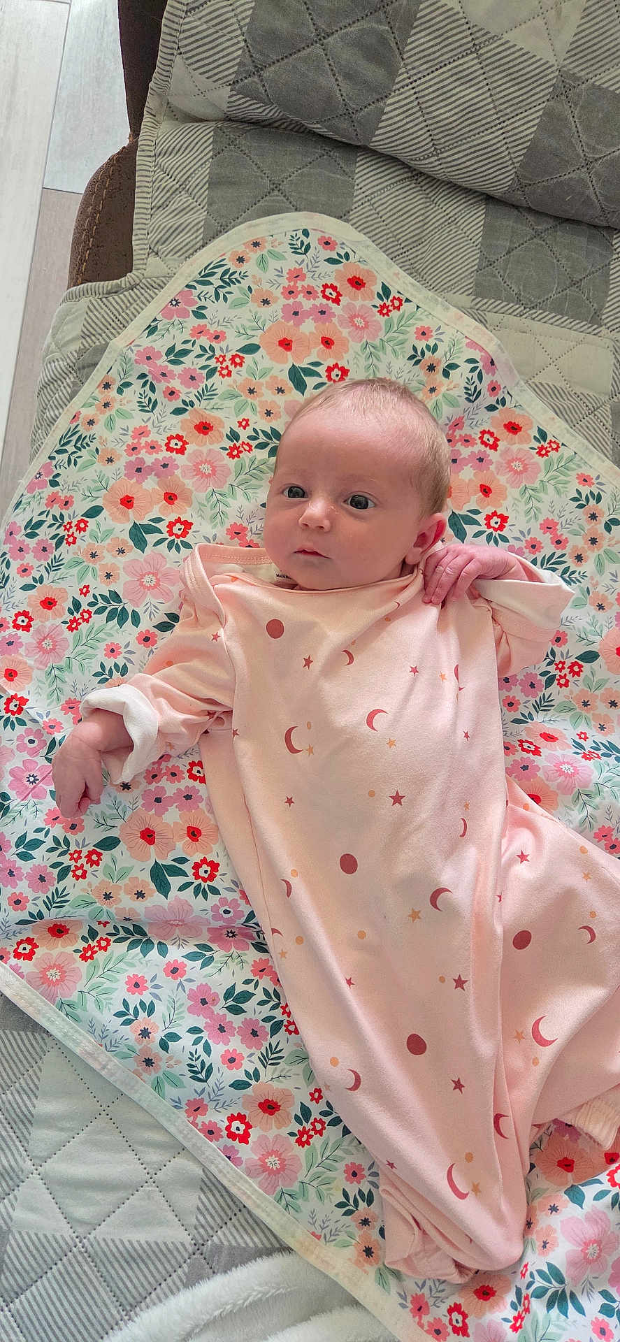 Rylynn is registered to the contest to win money with this photo: baby, infant, newborn, child, onesie, pink_clothing, floral_blanket, blanket, bedding, quilt, portrait, face, head, eyes_open, hand, lying_down, indoor, soft_lighting, cute, peaceful