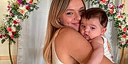 Ambre participe au concours pour gagner de l'argent avec cette photo : woman, baby, child, hug, embrace, smile, flower_arrangement, curtains, indoor, portrait, blonde_hair, casual_clothing, baby_clothing, happy, family, love, affection, skin, face, people