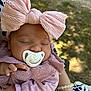 baby, sleeping, pacifier, headband, bow, pink_clothing, lace, hand, arm, outdoor, sunlight, person, infant, closeup, peaceful, cute, soft_light, nature, portrait, resting