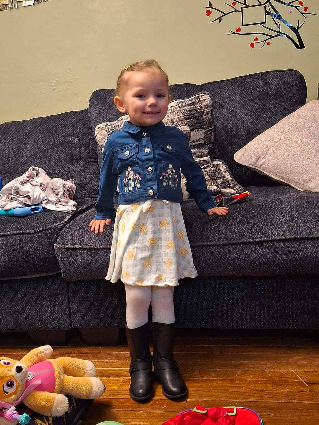 Annabelle is registered to the contest to win money with this photo: baby_toddler_clothing, boot, child, comfort, couch, event, fashion_design, floor, flooring, fun, joy, leg, living_room, person, room, sleeve, smile, snapshot, sneakers, sock