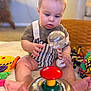 baby, child, toy, rattle, blanket, indoor, cute, sitting, playtime, infant, colorful, focus, soft_light, striped_clothing, feet, hands, face, expression, homedecor, carpet