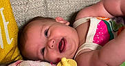 Megan is registered to the contest to win money with this photo: baby, smiling, pacifier, blanket, couch, pillow, infant, happy, face, child, clothing, colorful, soft, portrait, indoor, relaxing, cute, person, babywear, resting