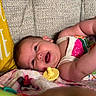 baby, smiling, pacifier, blanket, couch, pillow, infant, happy, face, child, clothing, colorful, soft, portrait, indoor, relaxing, cute, person, babywear, resting