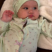 Megan joined the competition — help win amazing prizes! baby, infant, child, onesie, bonnet, floral_pattern, blanket, soft_fabric, couch, leather, cute, chubby_cheeks, portrait, indoors, relaxed, gazing, hand_raised, comfortable, cozy, young