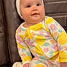 Megan joined the competition — help win amazing prizes! baby, child, onesie, floral_pattern, headband, couch, leather, blanket, infant, sitting, indoors, cute, face, person, smile, soft, colorful, clothing, young_child, cozy