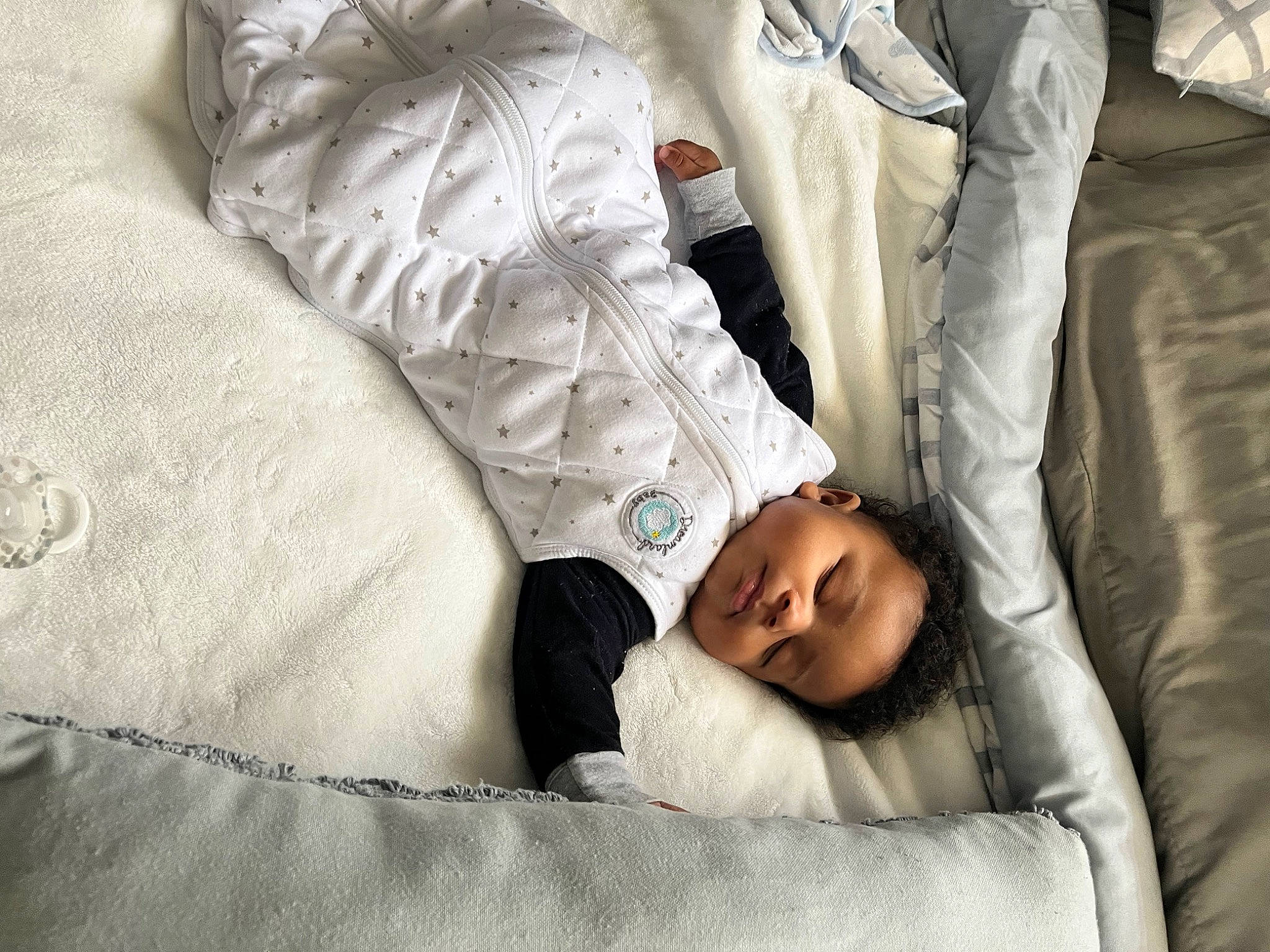 Shaun is registered to the contest to win money with this photo: baby, baby_sleeping, bed, bed_sheet, bedding, bedroom, bedtime, child, comfort, couch, gesture, head, human_leg, linens, mammal, person, room, sitting, sleeve, textile