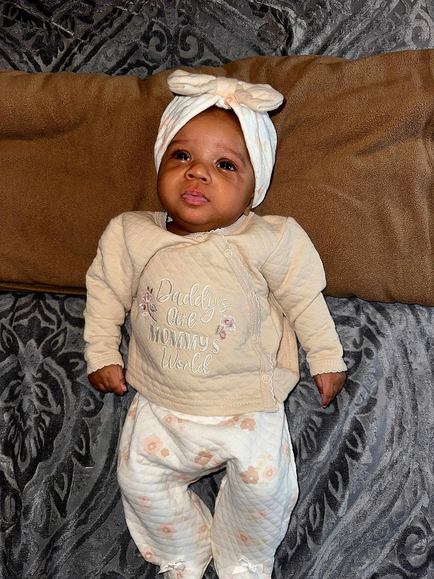Zipporah joined the competition — help win amazing prizes! baby, infant, child, quilted_clothing, headband, blanket, patterned_blanket, lying_down, cute, curious_expression, indoors, cozy, soft_lighting, person, portrait, small_hands, comfortable, warm, cute_outfit, text_on_clothing