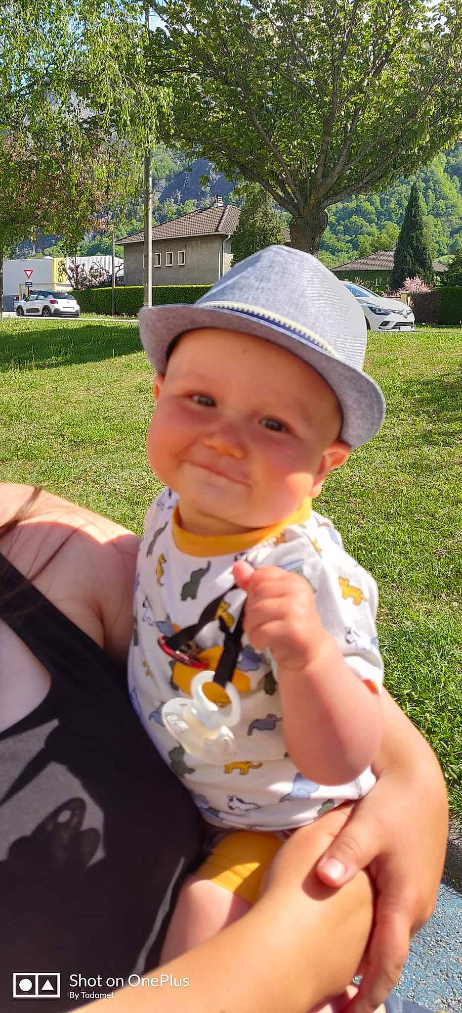 Logan participe au concours pour gagner de l'argent avec cette photo : baby, baby_toddler_clothing, cap, child, fashion_accessory, fedora, fun, grass, happy, hat, headgear, headwear, leisure, lip, person, plant, recreation, summer, sun_hat, toddler