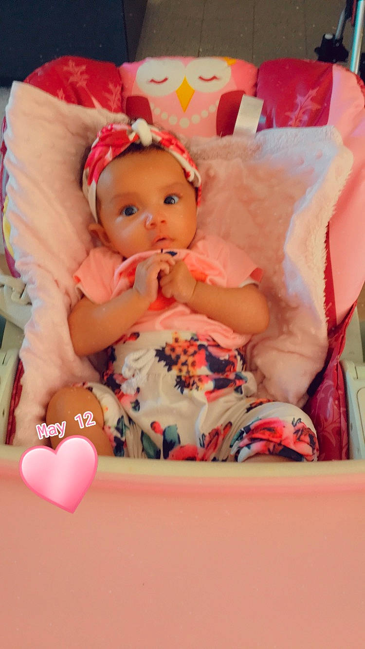 Inaya participe au concours pour gagner de l'argent avec cette photo : baby, baby_products, baby_toddler_clothing, chair, child, comfort, doll, happy, headband, headpiece, lap, magenta, pattern, peach, person, pink, sitting, sock, sweetness, textile