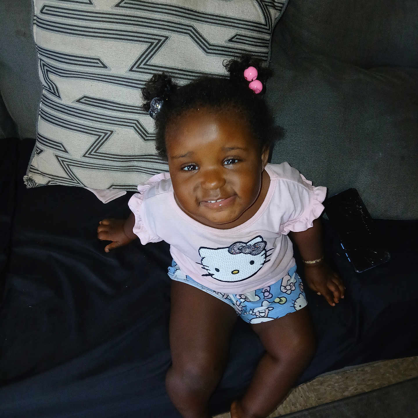 Shameria is registered to the contest to win money with this photo: barefoot, casual_clothing, child, couch, curly_hair, cute, hair_beads, happy, hello_kitty, indoor, living_room, person, pillow, pink_shirt, portrait, shorts, sitting, smiling, toddler, young_child