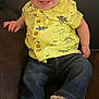 Hunter is registered to the contest to win money with this photo: baby, child, smiling, yellow_shirt, dinosaurs, jeans, white_sneakers, sitting, couch, indoor, happy, cute, portrait, infant, clothing, footwear, person, young_child, casual, relaxed